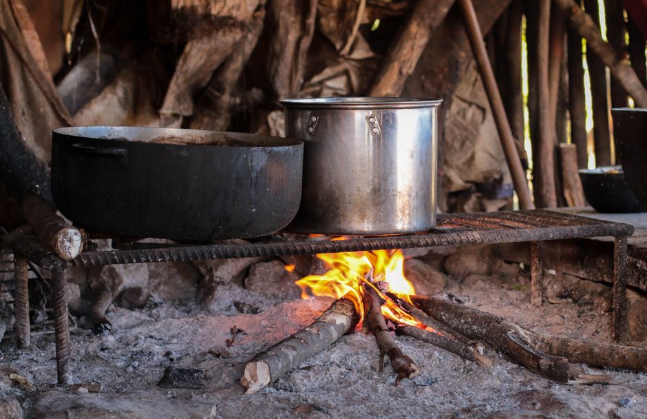 Two pots cooking over a campfire in a rustic outdoor setting, creating a warm ambiance.